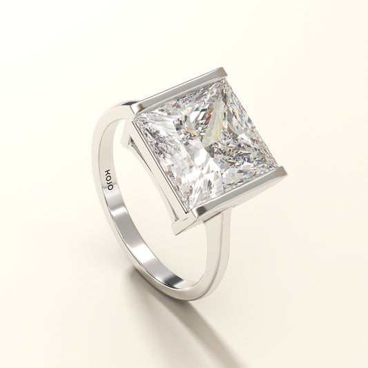 Diamond ring with a prominent princess-cut diamond on a light background.