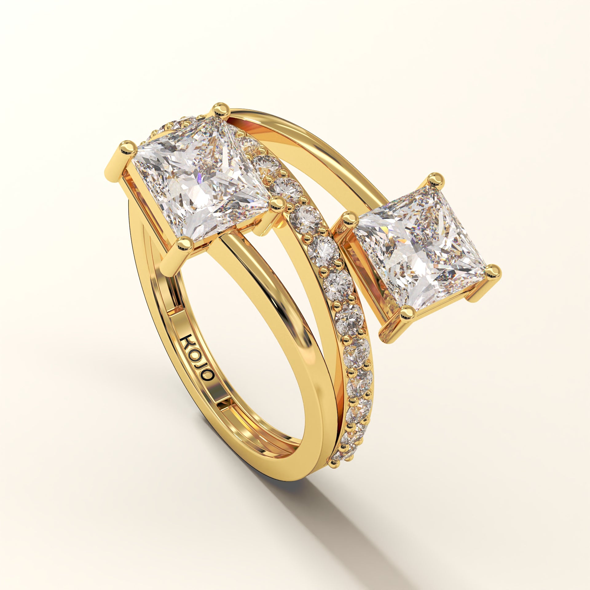 Prism Arc - 2 Princess Cut Diamond Ring with 17 Round Pavé Diamonds in 18K Yellow Gold. Total diamond 2.36 Carat with princess-cut stones on a light-beige background with "KOJO" branding (side-view).