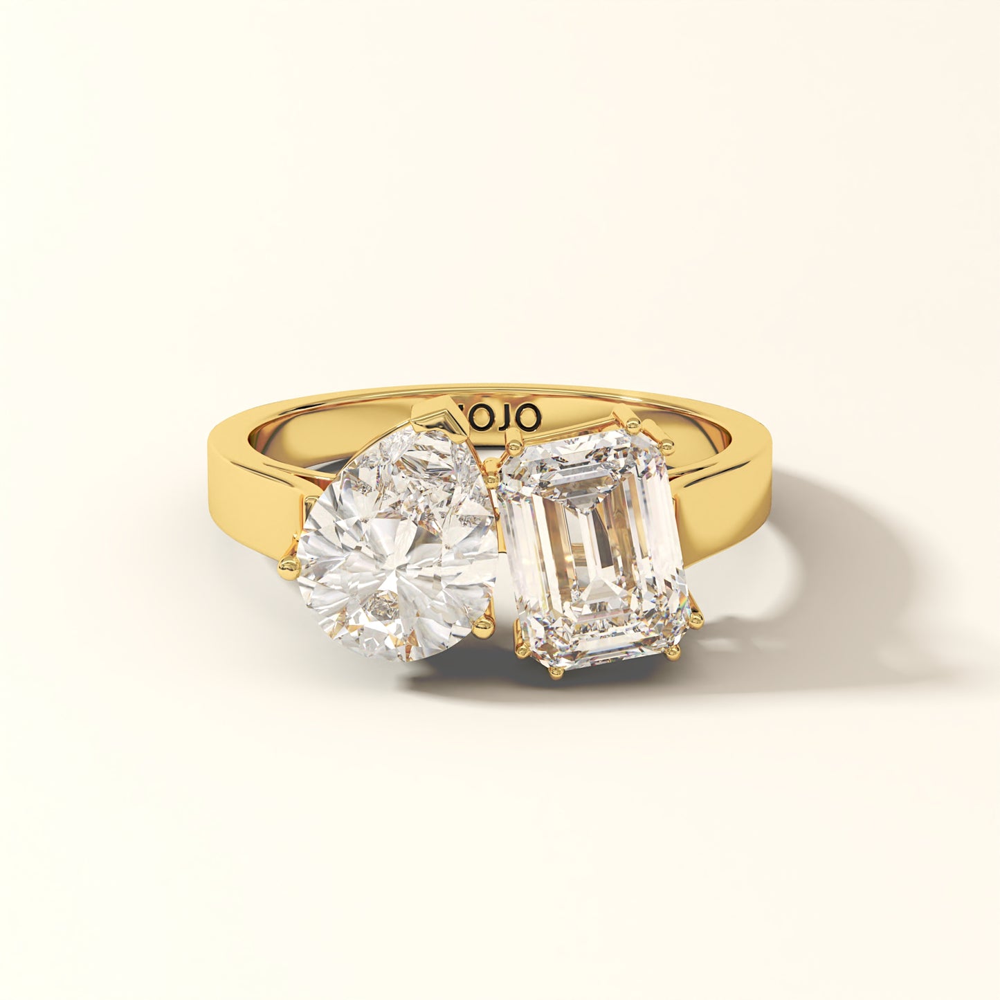 Duet Line - 3 Carat Emerald-cut diamond and Pear-cut Diamond Ring in 18K Yellow Gold with 'KOJO' branding on a light background.