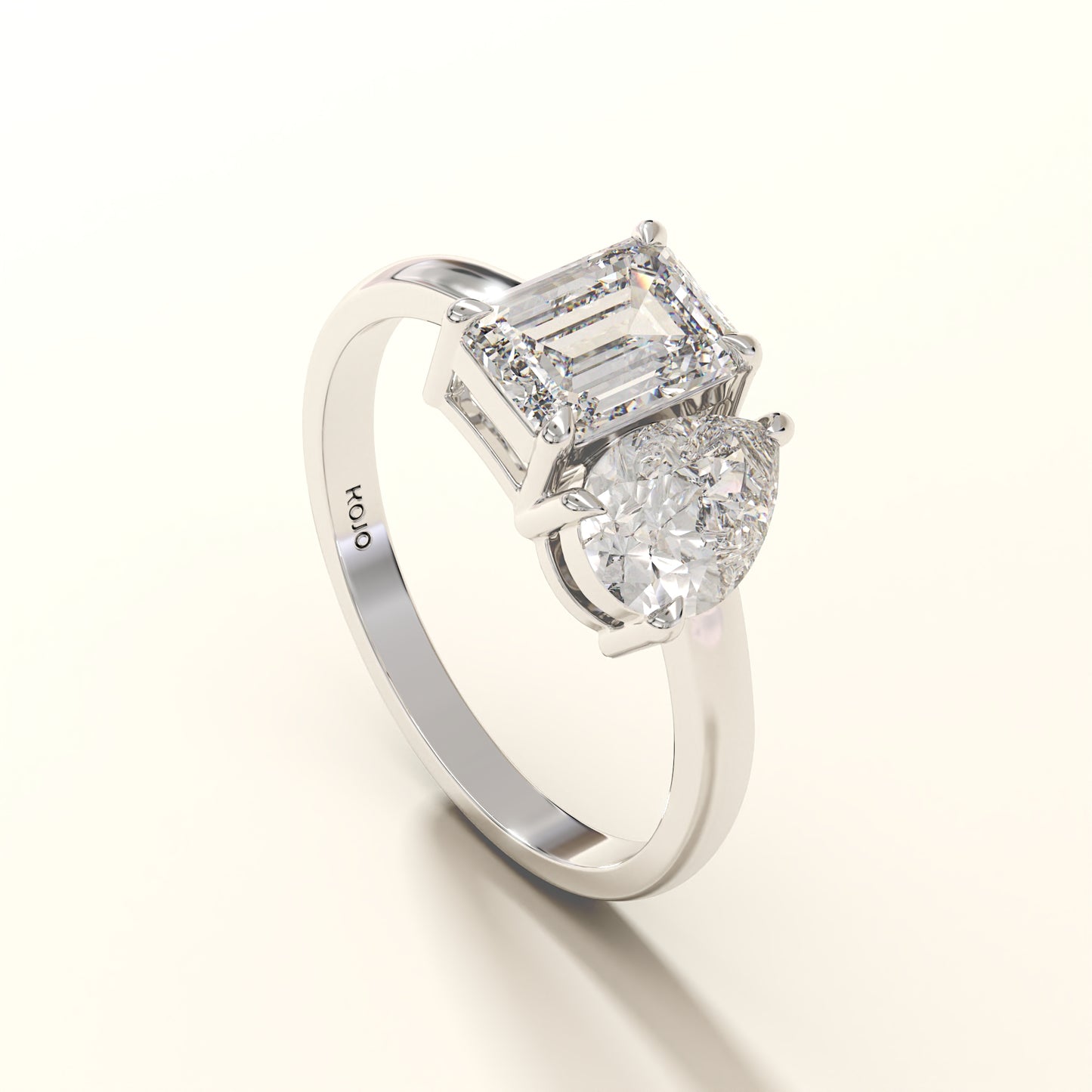 Diamond ring with two clear gemstones one emerald and one pear diamond on a white background