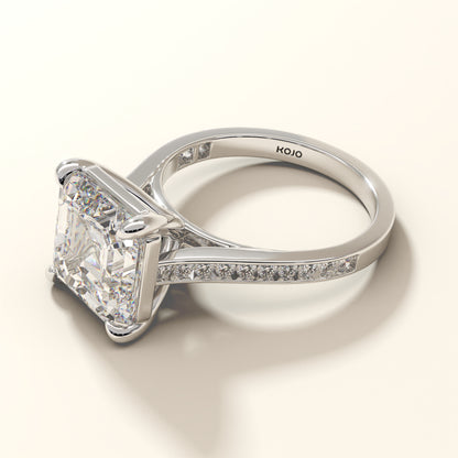 Silver ring with a large6 ct asscher diamond and round pave diamonds on the band, branded 'KOJO'.