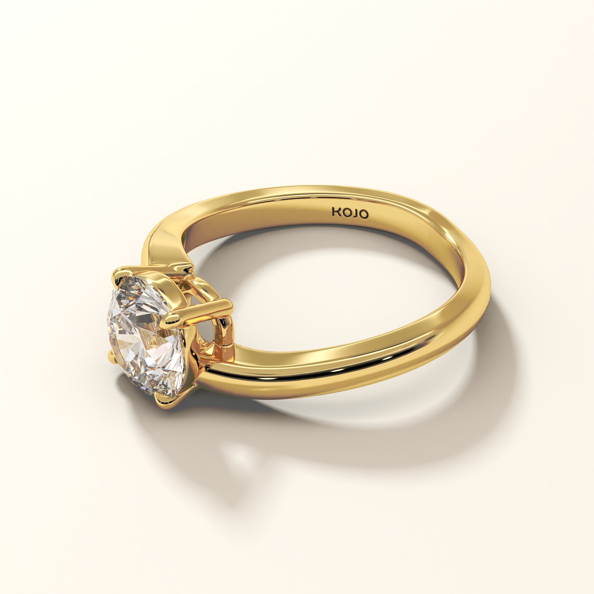 1.50 Carat Lab-Grown Round Brilliant Diamond Ring in 18K Yellow gold with "KOJO" Diamonds branding on a light background (top angle view). The Solara Arc Round Diamond Ring.