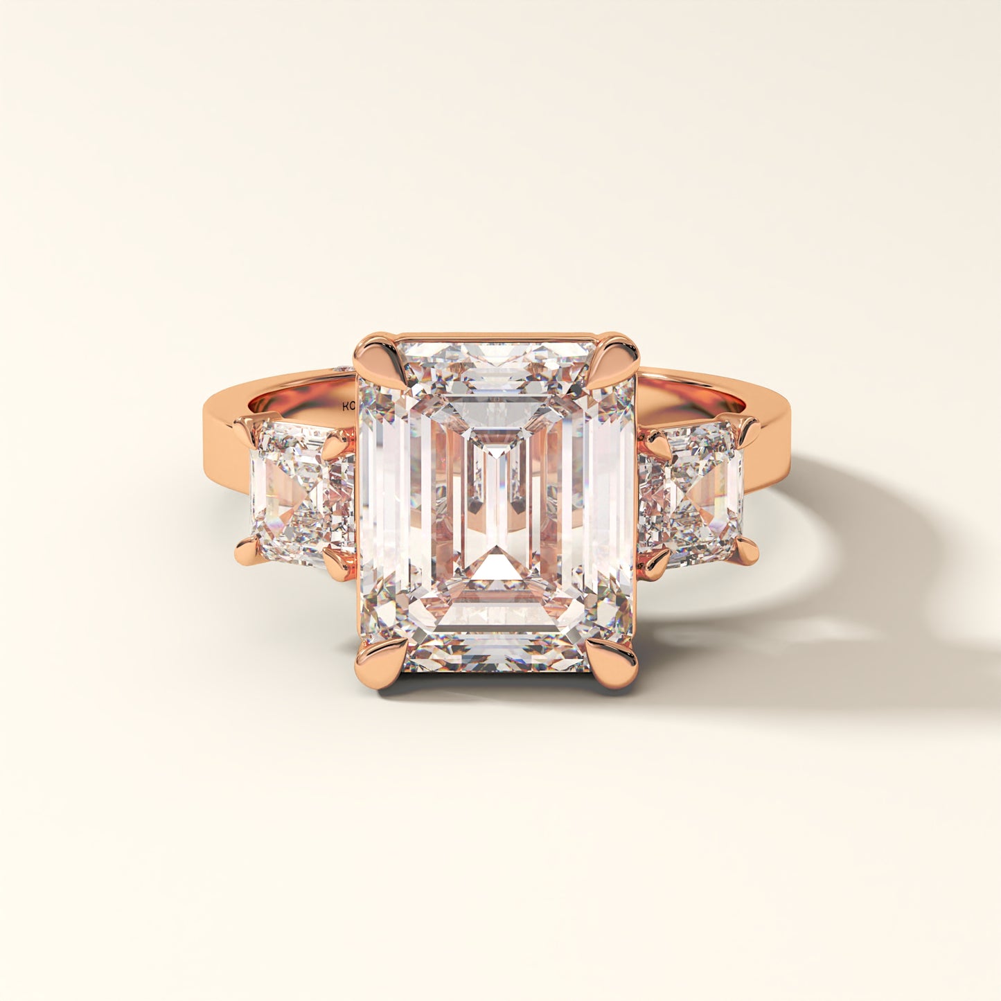 Rose gold ring with a large emerald-cut diamond and smaller side stones on a light background