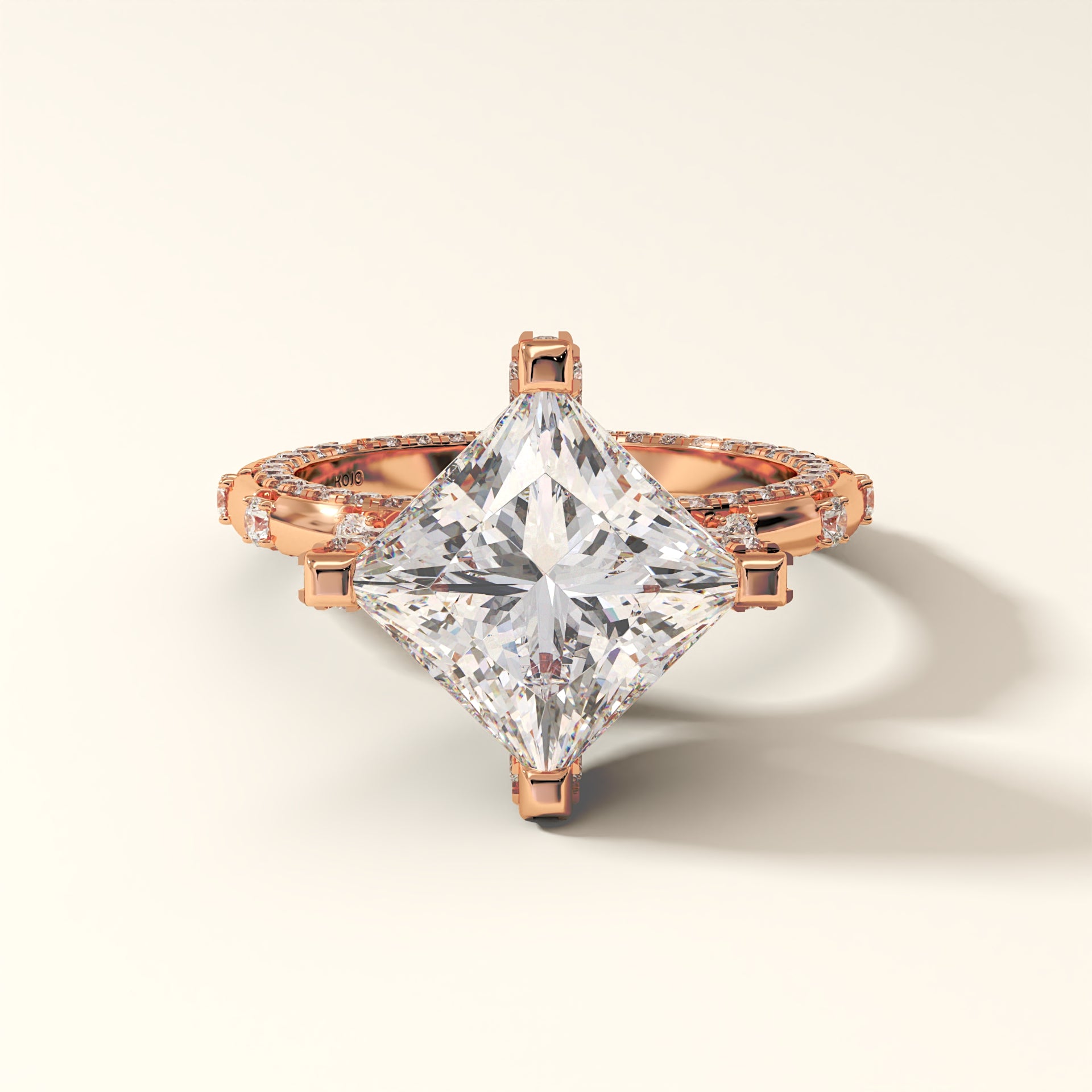 Rose gold ring with a large Princess diamond on a light beige background