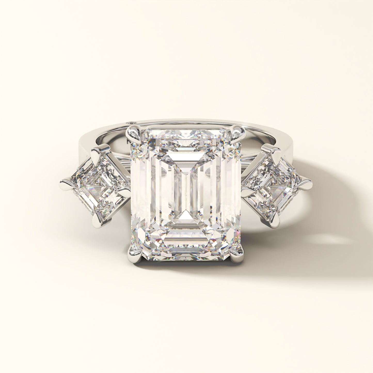 Emerald-cut lab-grown diamond three-stone engagement ring with matching side stones in 18K white gold.