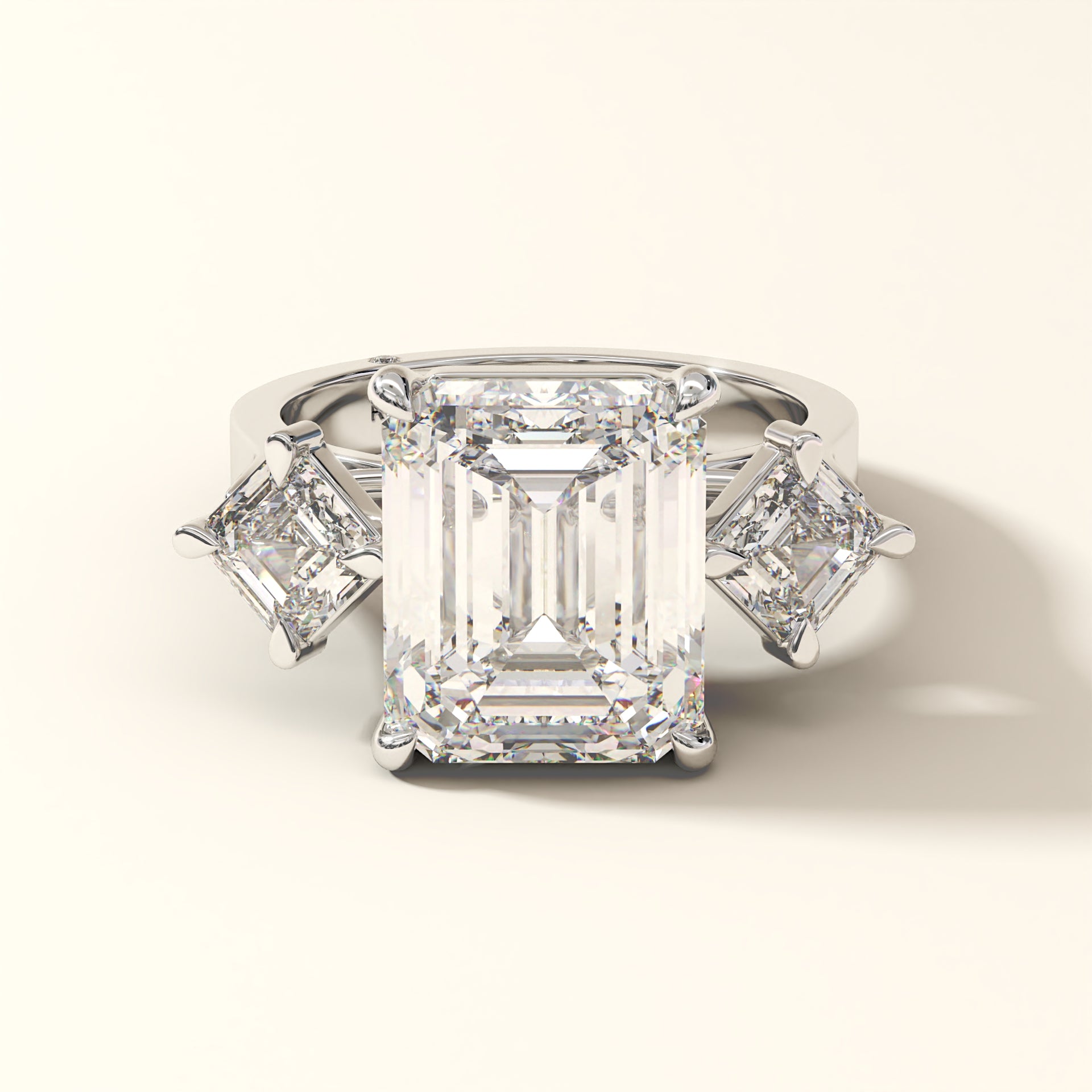 Emerald-cut lab-grown diamond three-stone engagement ring with matching side stones in 18K white gold.