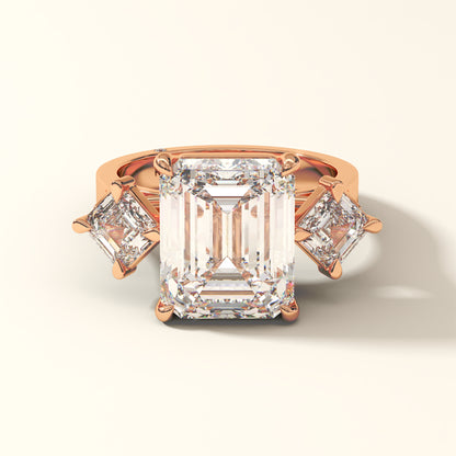 Rose gold ring with one large and two smaller emerald-cut diamonds on a white background