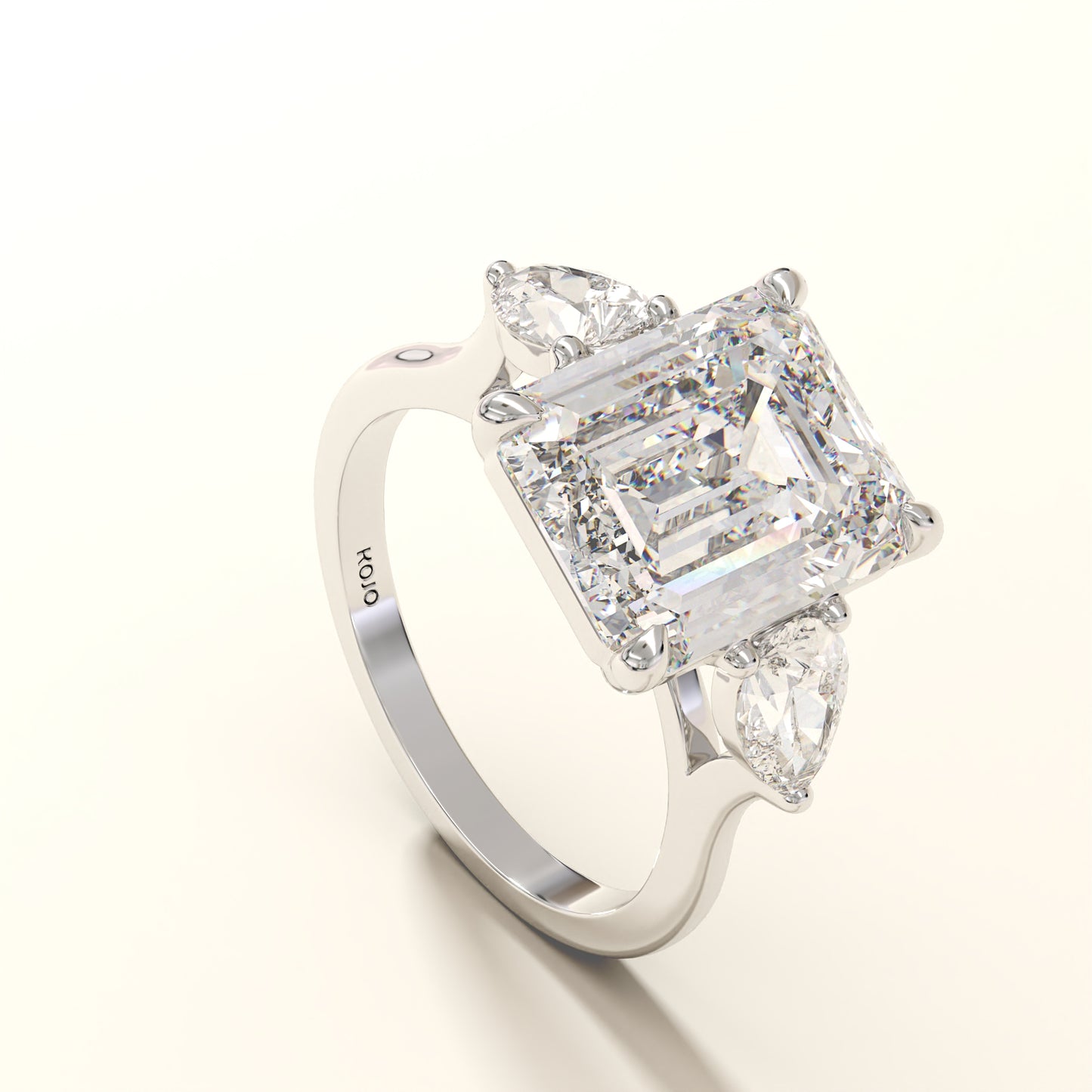 Diamond ring with emerald-cut center stone and pear side stones on a white background