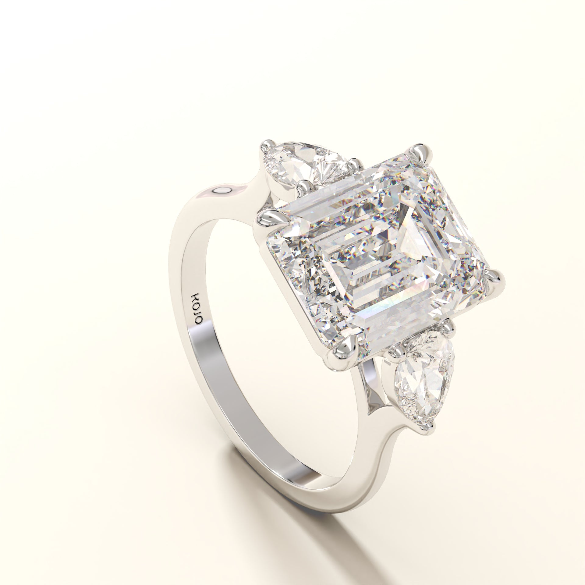 Diamond ring with emerald-cut center stone and pear side stones on a white background